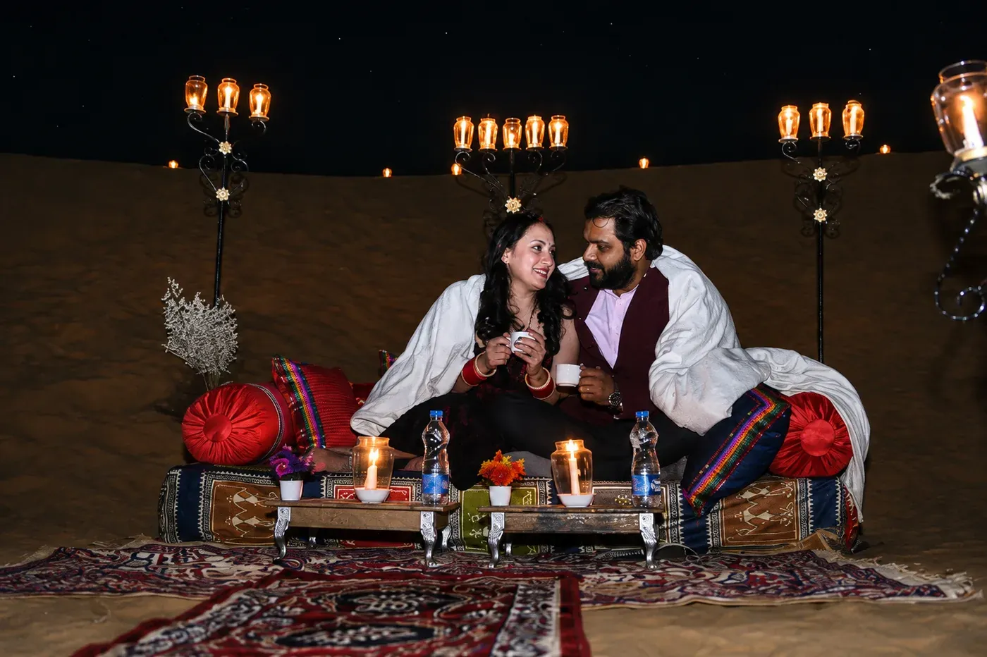 Couple enjoying private candlelight dinner on the sand dunes under the starlit desert sky