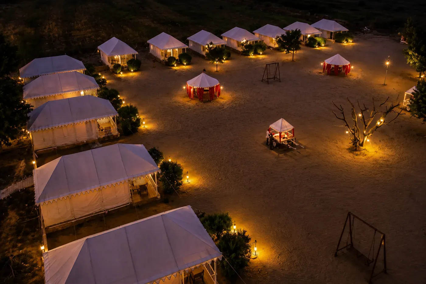High-angle aerial night view of illuminated Swiss tents and desert grounds