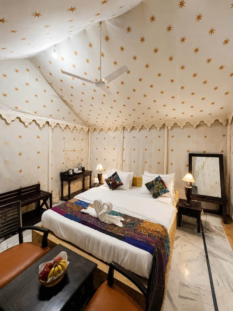 Spacious Super Deluxe tent bedroom with swan towel art, fresh fruit basket and dressing mirror